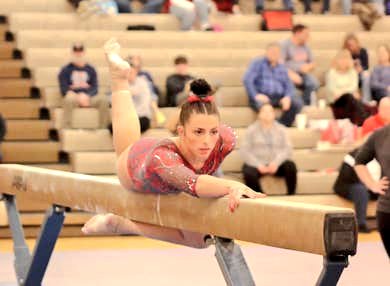 Student on a balance beam performing gymnastics